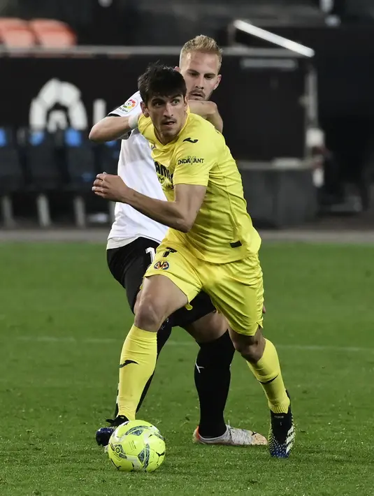 Penyerang Villarreal, Gerard Moreno membawa bola dari kawalan gelandang Valencia, Uros Racic pada pertandingan lanjutan La Liga Spanyol di stadion Mestalla di Valencia (6/3/2021). Valencia kini mengkoleksi 30 poin dari 26 laga. (AFP/Jose Jordan)