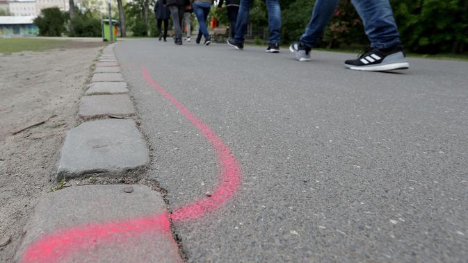 Seorang pria berjalan melewati garis berwarna pink yang diperuntukkan bagi bandar narkotika di Taman Goerlitzer, Berlin, 9 Mei 2019. Nantinya, para bandar hanya boleh bertransaksi di dalam zona berupa coretan kotak dengan cat semprot berwarna pink itu saja. (AP Photo/Michael Sohn)