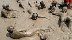 Anak-anak berendam dalam lumpur saat berpartisipasi dalam Mud Day atau Hari Lumpur di Michigan, negara bagian AS, Selasa (9/7/2019). Para peserta perayaan yang menjadi tradisi setiap tahun ini merupakan anak-anak untuk agar mereka bersenang-senang selama liburan musim panas.  (AP/Carlos Osorio)