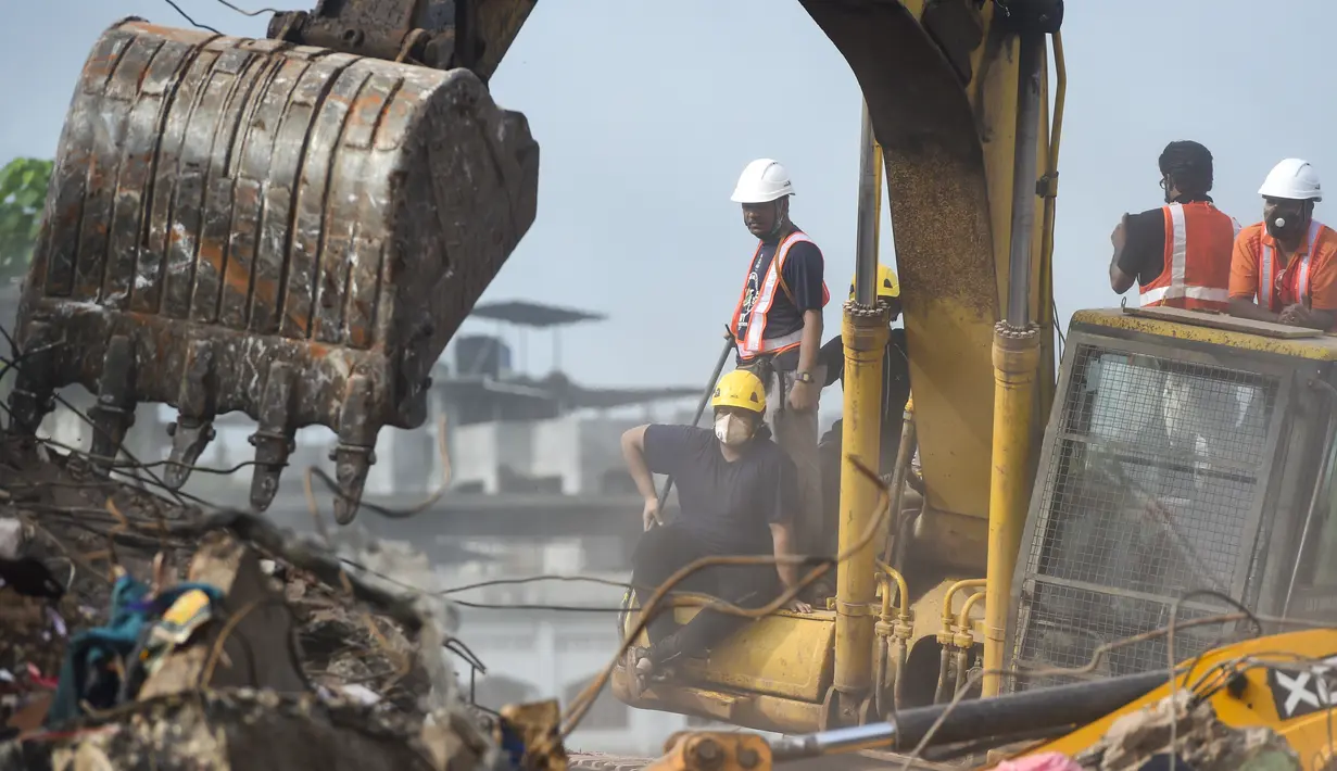 Petugas penyelamat mencari korban di reruntuhan gedung apartemen yang runtuh di Mahad, India (25/8/2020). Tim penyelamat dan anjing pelacak menyisir puing-puing mencari yang selamat setelah gedung apartemen berlantai lima runtuh. (AFP Photo/Punit Paranjpe)