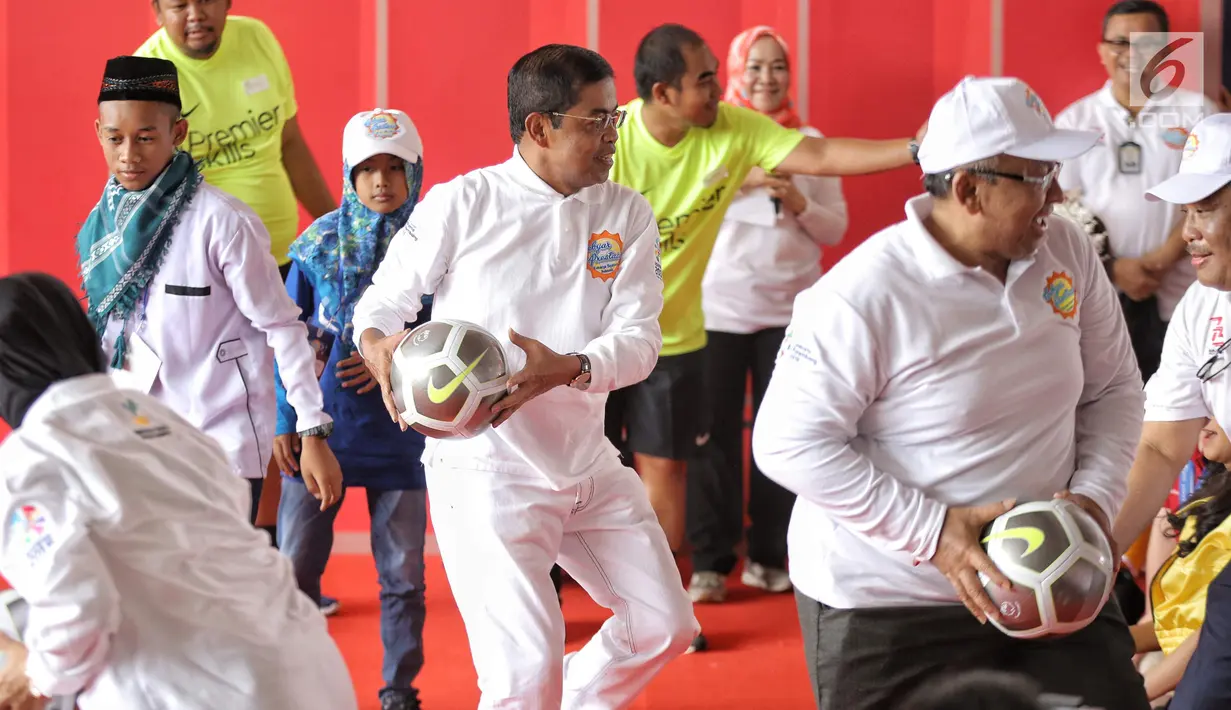 Menteri Sosial (Mensos) Idrus Marham bermain bola dalam acara Gebyar Prestasi Keluarga Sejahtera Indonesia 2018 di Cibubur, Minggu (12/8). Acara diikuti oleh enam ribu peserta anak-anak berprestasi se-Indonesia. (LIputan6.com/Faizal Fanani)