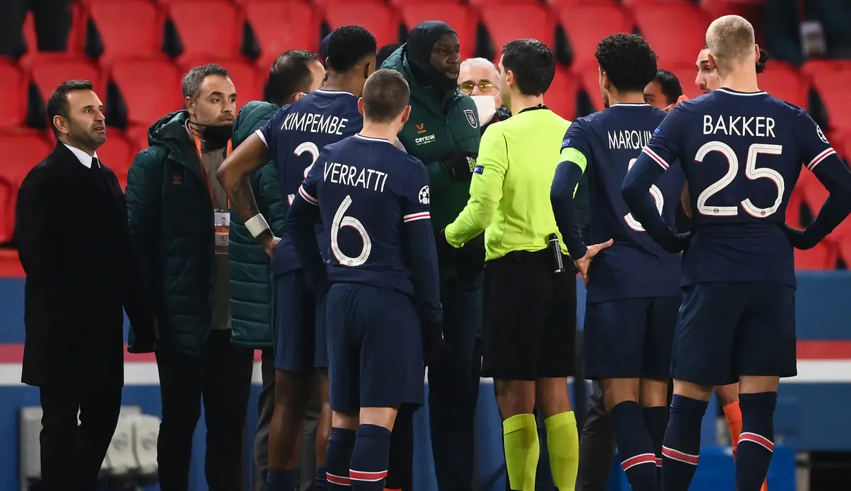 Gelandang Istanbul Basaksehir, Demba Ba (tengah), berbicara dengan wasit Ovidiu Hategan, usai dihentikannya laga lanjutan Liga Champions Grup H melawan Paris Saint-Germain di Parc des Princes Stadium, Selasa (8/12/2020). (AFP/Franck Fife)