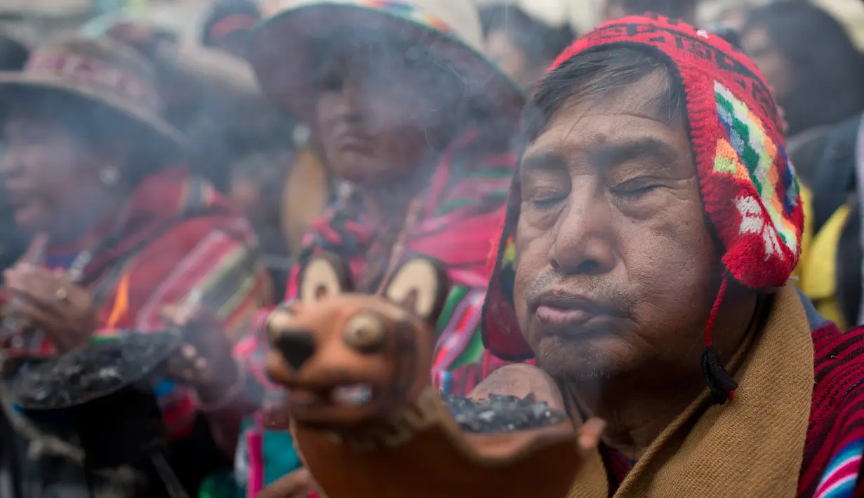 Anggota komunitas Andes membawa guci dengan dupa yang terbakar dalam sebuah arak-arakan patung dewa Ekeko di La Paz, Bolivia (23/1). Porsesi ini merupakan bagian dari acara pameran miniatur Alasita. (AP Photo / Juan Karita)