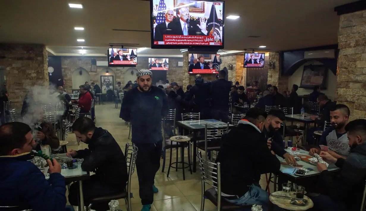 Warga Palestina berada di kafe di kota Ramallah di Tepi Barat saat sebuah siaran televisi menayangkan pidato Presiden AS, Donald Trump mengumumkan AS mengakui Yerusalem sebagai ibu kota Israel (6/12). (AFP Photo/Abbas Momani)