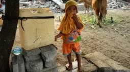 Seorang anak berdiri di depan rumahnya yang rusak akibat gempa di kecamatan Kayangan di Lombok Utara, Rabu (8/8). BPBD Lombok Utara mencatat data sementara jumlah korban jiwa akibat gempa Lombok mencapai 347 orang. (AFP/SONNY TUMBELAKA)