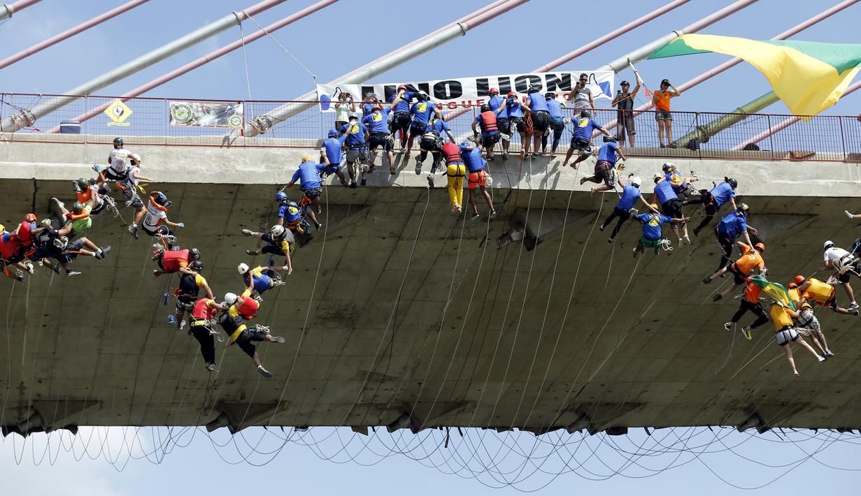 Ratusan orang saat melompat menggunakan tali dari jembatan yang memiliki ketinggian 30 meter di Hortolandia, Brasil, Minggu (10/4). Sebanyak 149 orang mencoba membuat rekor dunia dengan melompat bersama dari atas jembatan. (REUTERS/Paulo Whitaker)