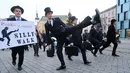Seorang pria mengenakan kostum berjalan dengan mengangkat tinggi kakinya di Brno, Republik Ceko (7/1). Mereka mengenakan kostum tersebut untuk mengenang grup komedi asal Inggris, Monty Python. (AFP Photo/Radek Mica)