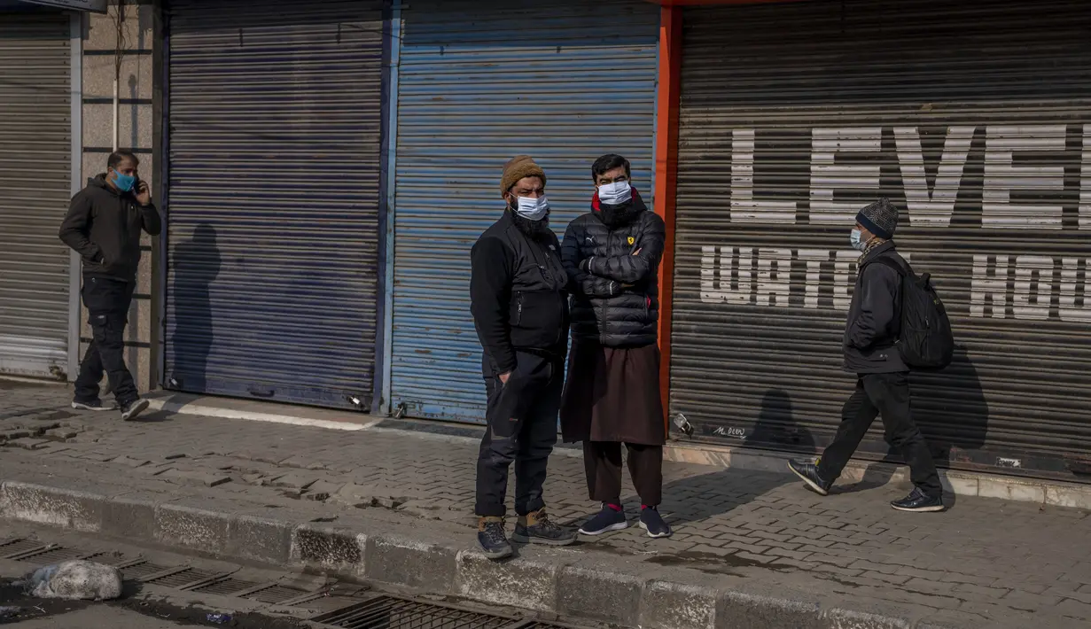 Warga Kashmir berdiri di luar toko mereka setelah mereka diperintahkan untuk menutup toko mereka oleh pihak berwenang selama penguncian akhir pekan di Srinagar, Kashmir yang dikuasai India, Sabtu (15/1/2022). (AP Photo/Dar Yasin)