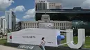 Seorang wanita berjalan melewati patung berbentuk topeng di depan Balai Kota Seoul di Seoul (4/9/2020). Korea Selatan melaporkan 198 kasus Covid-19 baru pada 4 September, hari ke-22 berturut-turut meningkat tiga digit. (AFP/Jung Yeon-je)