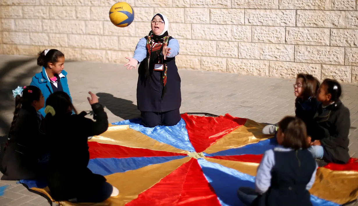 Hiba Al-Sharfa bermain bola bersama muridnya di sekolah Asosiasi Hak Hidup di Kota Gaza (21/12). Hiba Al-Sharfa telah membuktikan bahwa Down Syndrome tidaklah menjadi hambatan untuk meraih cita-citanya. (Reuters/Suhaib Salem)