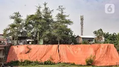 Terpal besar menutupi lokasi tanah longsor di pinggir Kanal Banjir Timur, Jakarta, Kamis (18/6/2020). Longsor yang terjadi pada awal Januari 2020 tersebut belum diperbaiki dan hanya ditutupi terpal besar guna mengantisipasi longsor susulan. (merdeka.com/Iqbal S. Nugroho)