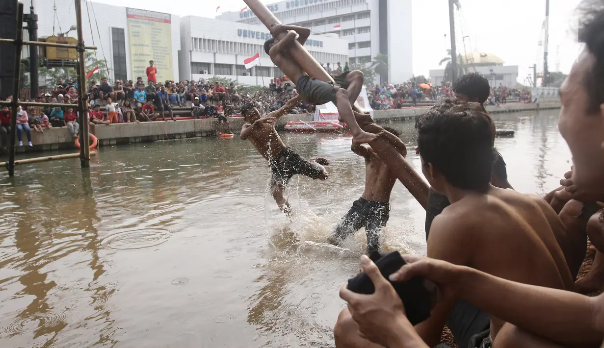 Seorang peserta terjatuh saat mengikuti lomba panjat pinang dalam Festival Kalimalang di Cipinang Melayu, Jakarta Timur, Kamis (17/8). Festival Kalimalang ini dalam rangka memeriahkan HUT ke-72 RI. (Liputan6.com/Herman Zakharia)