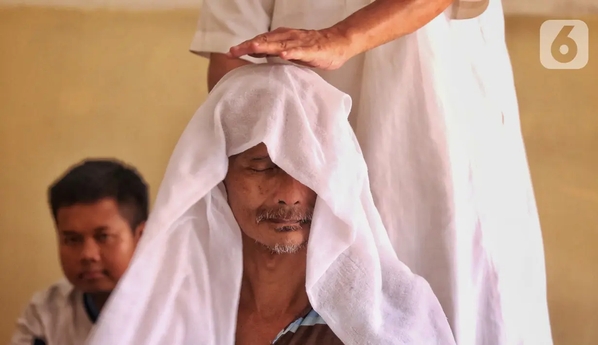 Ustad Abdul Razaq melakukan teknik penyembuhan dengan melakukan pemijitan syaraf yang disertai bacaan ayat-ayat suci Alquran.  (Liputan6.com/Angga Yuniar)