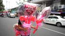Seorang pria membawa balon berbentuk hati di pasar bunga di Manila, Filipina, Senin (13/2/2023). Harga bunga naik karena tingginya permintaan sehari sebelum Hari Valentine. (AP Photo/Aaron Favila)