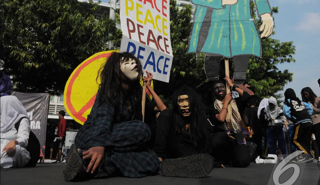 Dua pria bertopeng membawa tulisan 'Peace' saat aksi 'Jaga Jakarta'   di kawasan Bunderan HI, Jakarta, Minggu (23/11/2014).   (Liputan6.com/Herman Zakharia)