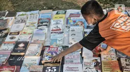 Seorang anak memilih buku saat kehadiran Perpustakaan Keliling di kawasan Kampung Melayu, Jakarta, Minggu (16/8/2020). Kegiatan sosial ini menghadirkan latihan tari, donasi pakaian layak, makanan, serta masker. (merdeka.com/Iqbal S. Nugroho)