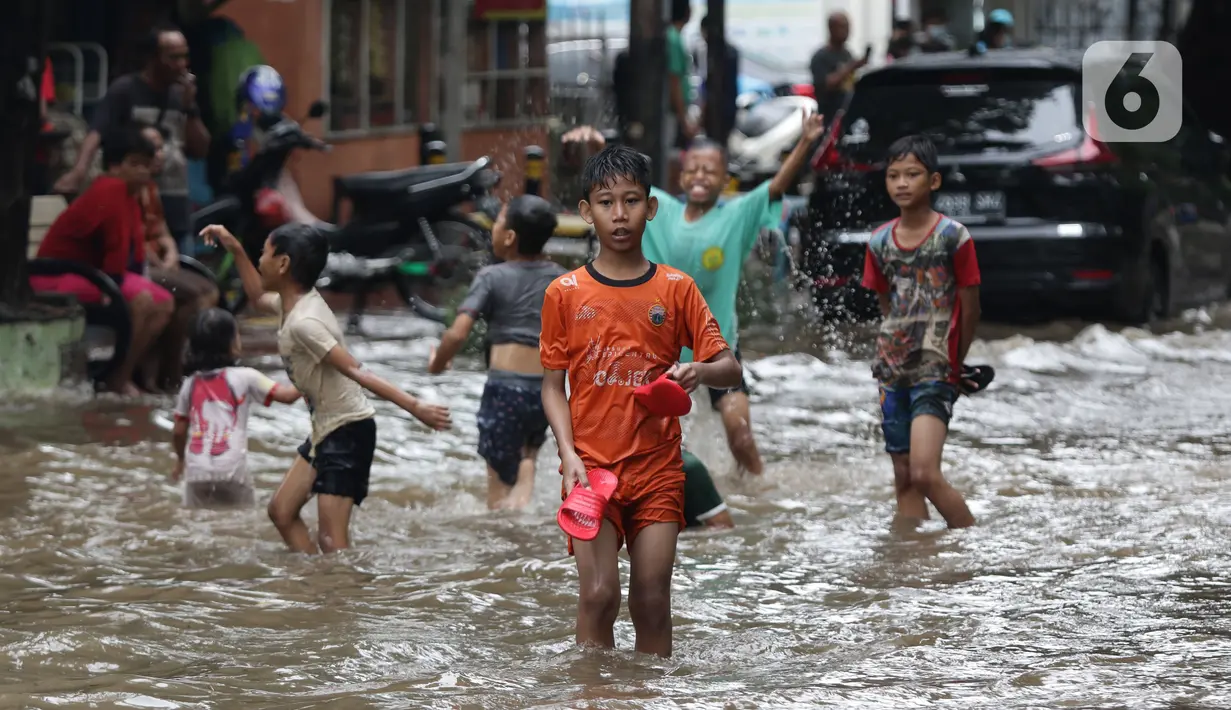 Anak anak bermain air di sebagian Jalan Bungur Besar Raya yang tergenang, Jakarta, Selasa (18/1/2022). Genangan air di sebagian Jalan Bungur Besar Raya dimanfaatkan anak-anak untuk bermain meski berbahaya. (Liputan6.com/Helmi Fithriansyah)
