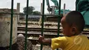 Seorang bocah melihat ekskavator di pinggir rel kereta api. Orangtua mereka memilih bertahan di kasan Bongkaran karena tak punya uang untuk menyewa rumah, Tanah Abang, Jakarta, Rabu (21/1/2015). (Liputan6.com/Miftahul Hayat)