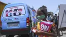 Seorang gadis pergi dengan makanan ringan setelah memberikan sampel swab untuk menguji virus corona Covid-19 di dalam sebuah van di New Delhi, India (1/7/2021).  Kegiatan ini diselenggarakan oleh Polisi Delhi bekerja sama dengan lab Star Imaging and Path. (AFP/Prakash Singh)