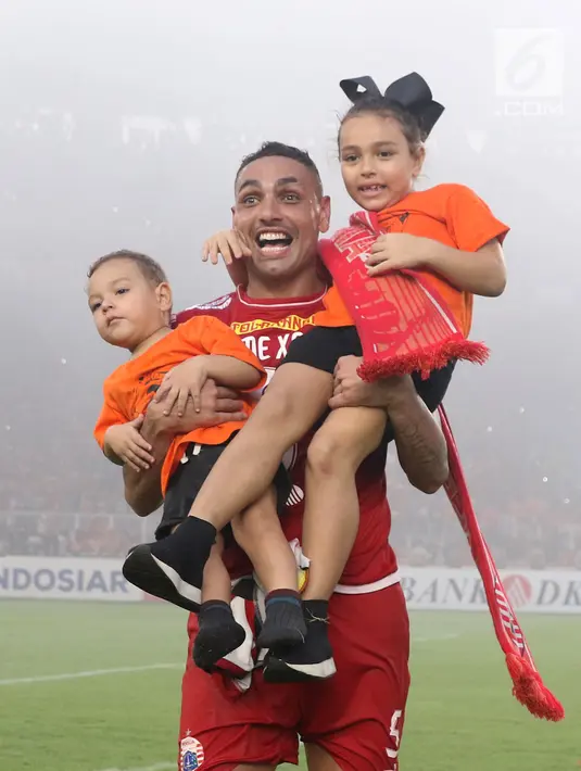 Bek Persija, Jaimerson Da Silva Xavier menggendong anak anaknya saat merayakan gelar juara Go-Jek Liga 1 Indonesia 2018 bersama Bukalapak di Stadion GBK, Jakarta, Minggu (9/12). Persija meraih juara dengan 62 poin. (Liputan6.com/Helmi Fithriansyah)