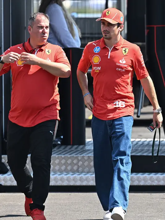 Pembalap Monegasque Ferrari, Charles Leclerc (kanan) dan seorang anggota tim tiba di lintasan balap Hungaroring di Mogyorod dekat Budapest pada 18 Juli 2024, menjelang Grand Prix Formula Satu Hongaria. (Attila KISBENEDEK/AFP)