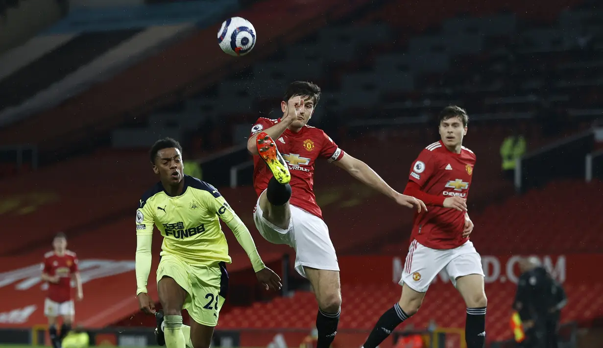 Bek Manchester United (MU), Harry Maguire (tengah) bersaing dengan gelandang Newcastle United, Joe Willock pada pekan ke-25 Liga Inggris 2020/2021  di Old Trafford, Senin (22/2/2021) dini hari WIB. Manchester United sukses membungkam Newcastle dengan skor 3-1. (Phil Noble/Pool via AP)