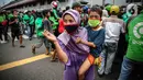 Seorang wanita menggendong anak  kecil saat mengantre nasi kotak serta masker dari TNI di Markas Komando Gabungan Wilayah I, Jakarta, Selasa (21/4/2020). Dalam rangka Hari Kartini, TNI membagikan makanan dan masker kepada masyarakat. (Liputan6.com/Faizal Fanani)