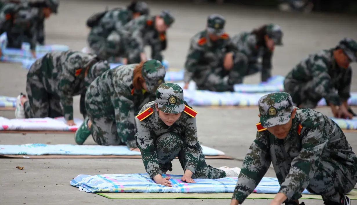 Mahasiswa baru belajar melipat selimut selama sesi pelatihan militer di sebuah kampus di Yangzhou, Jiangsu, China, Jumat (6/9/2019). Rangkaian ospek mahasiswa baru di China umumnya tidak melibatkan senior, melainkan tenaga pengajar hingga perwakilan militer. (STR/AFP)