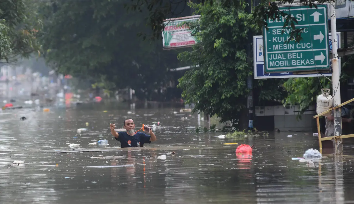 Warga berjalan di tengah banjir di Perumahan Vila Nusa Indah 3, Kabupaten Bogor, Jawa Barat, Selasa (4/3/2025). (merdeka.com/Arie Basuki)