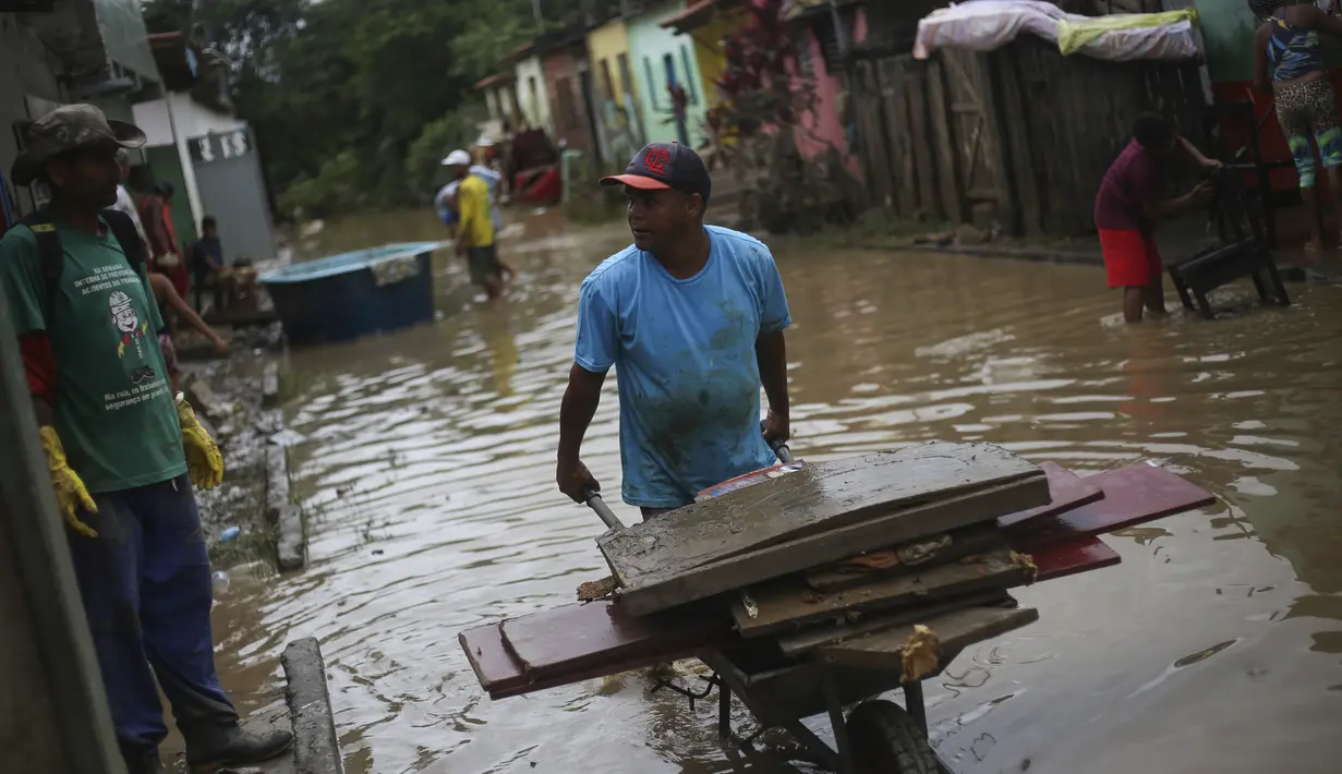 Warga membersihkan rumah mereka yang terendam banjir di Itapetinga, negara bagian Bahia, Brasil, Selasa (28/12/2021). Banjir menyebabkan ribuan orang terpaksa mengungsi dari rumah mereka . (AP/Raphael Muller)