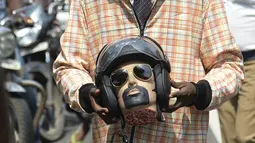 Seorang sukarelawan berpakaian seperti pengendara sepeda motor memegang kepala mockup dengan helm mengambil bagian dalam kampanye kesadaran keselamatan jalan dengan petugas polisi di Chennai (7/7/2021). (AFP/Arun Sankar)