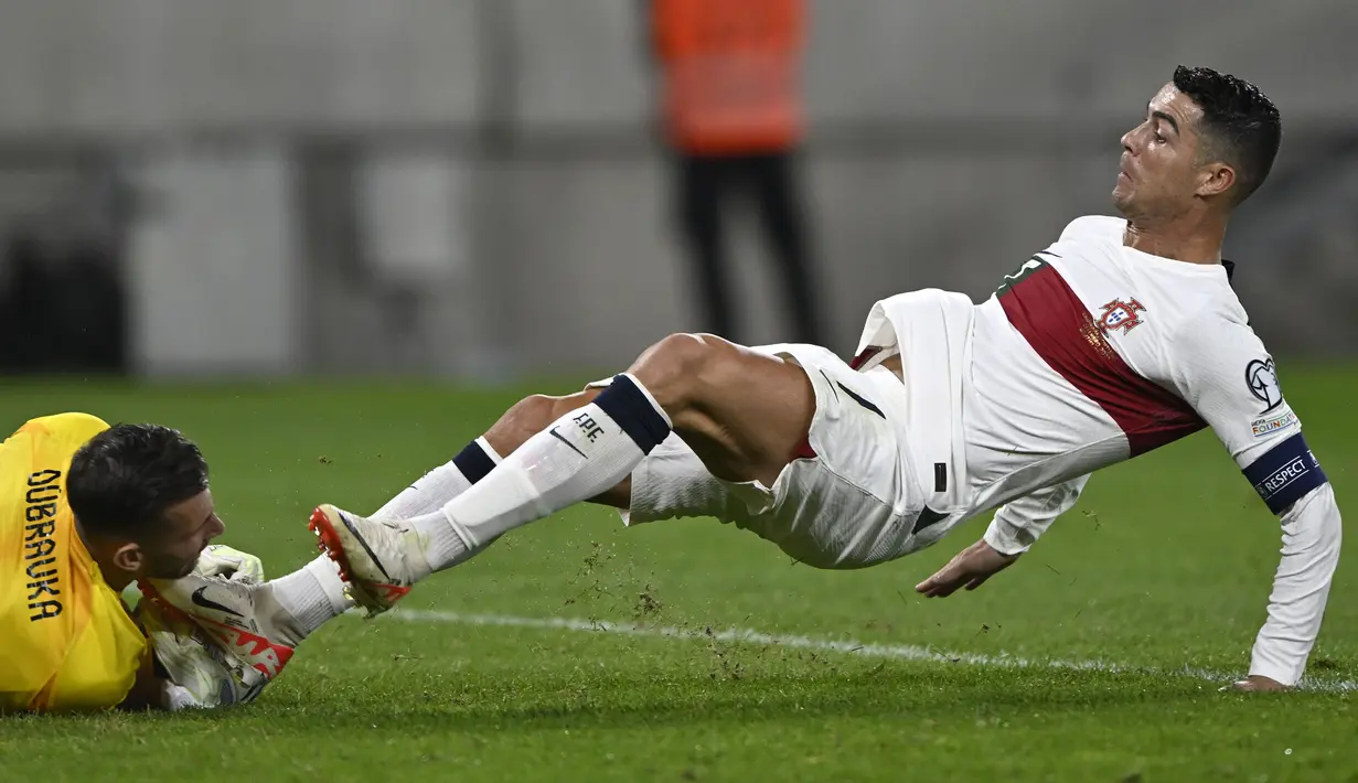 Pemain Portugal, Cristiano Ronaldo (kanan) berusaha merebut bola dari kiper Slovakia, Martin Dubravka saat laga grup G Kualifikasi Euro 2024 di National Football Stadium in Bratislava, Slovakia, Sabtu (9/9/2023) dini hari WIB. (AP Photo/Radovan Stoklasa)
