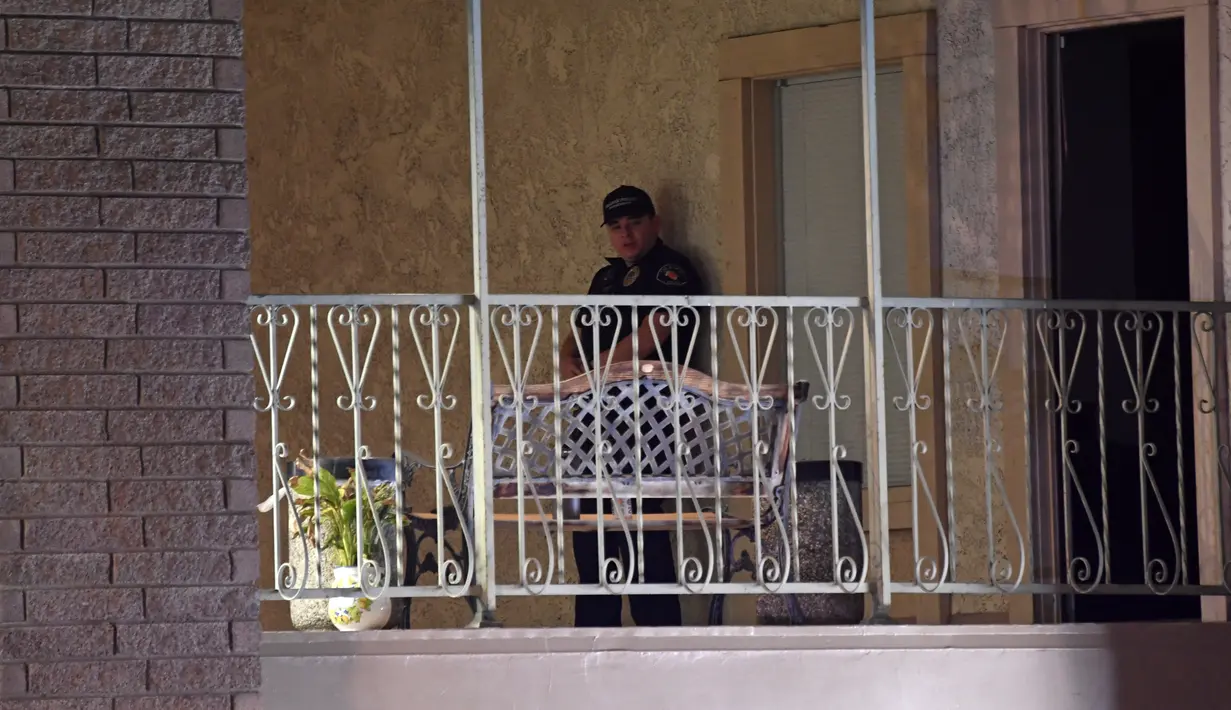 Seorang petugas polisi berdiri di sebuah gedung perkantoran di mana beberapa orang tewas dalam penembakan di Orange, California (31/3/2021).  Tersangka ditahan dan juga dibawa ke rumah sakit. (AFP/Patrick T. Fallon)