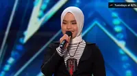 Gadis 17 tahun itu muncul di atas panggung dalam balutan kaus bergaris yang dipadukan jaket hitam dan hijab warna putih.