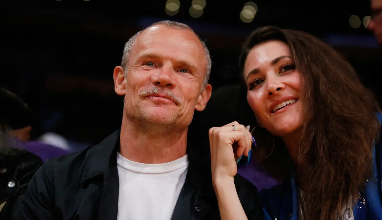 Musisi Michael Peter Balzary atau yang lebih dikenal dengan nama panggung Flea (kiri) menonton pertandingan NBA antara Los Angeles Lakers melawan Washington Wizards di Los Angeles (28/3). (AP Photo/Danny Moloshok)
