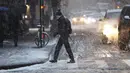 Pejalan kaki melintas saat salju mulai turun di Manhattan, New York, Kamis (15/11). Layanan Cuaca Nasional memprediksi hujan salju pertama pada awal musim dingin itu akan mencapai ketebalan 2-4 inci. (Angela Weiss / AFP)