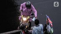 Pengendara motor membeli jas ponco saat hujan mengguyur Jakarta, Senin (26/10/2020). BPBD DKI Jakarta mengeluarkan peringatan dini cuaca berupa potensi terjadinya hujan lebat disertai petir dan angin kencang dampak dari siklon tropis Molave hingga 27 Oktober 2020. (merdeka.com/Iqbal S. Nugroho)