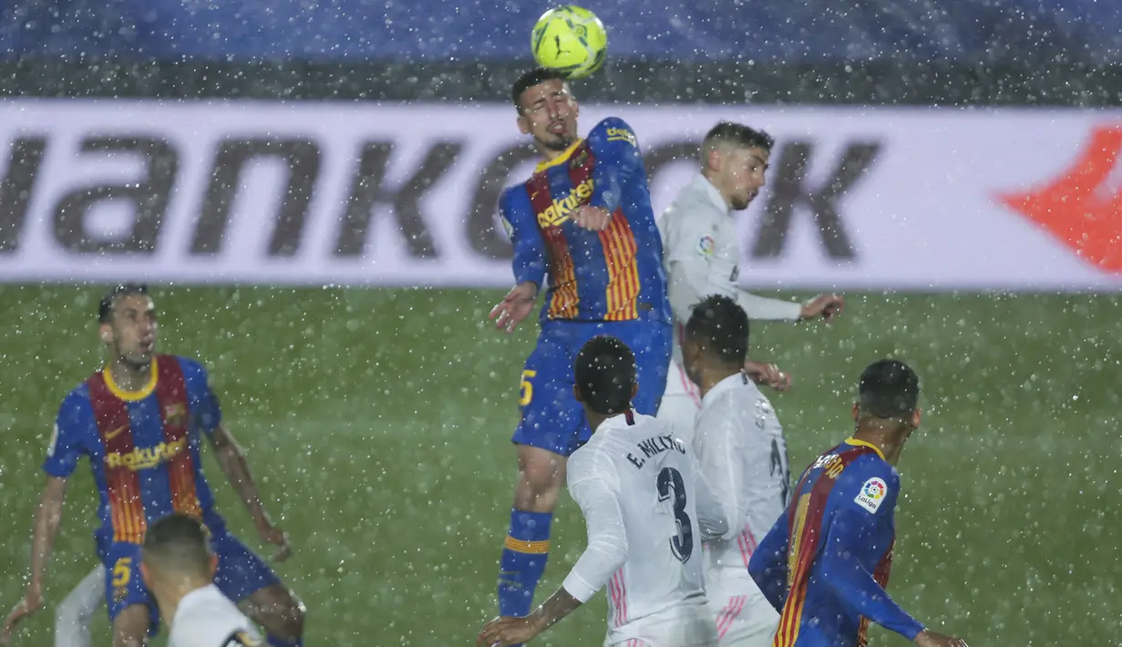 Gelandang Barcelona, Sergio Busquets (kiri atas) dan gelandang Real Madrid, Federico Valverde duel di udara pada pekan ke-30 Liga Spanyol di Estadio Alfredo Di Stefano, Minggu dinihari WIB (11/4/2021). Real Madrid kembali sukses taklukkan rival abadinya Barcelona 2-1. (AP Photo/Manu Fernandez)