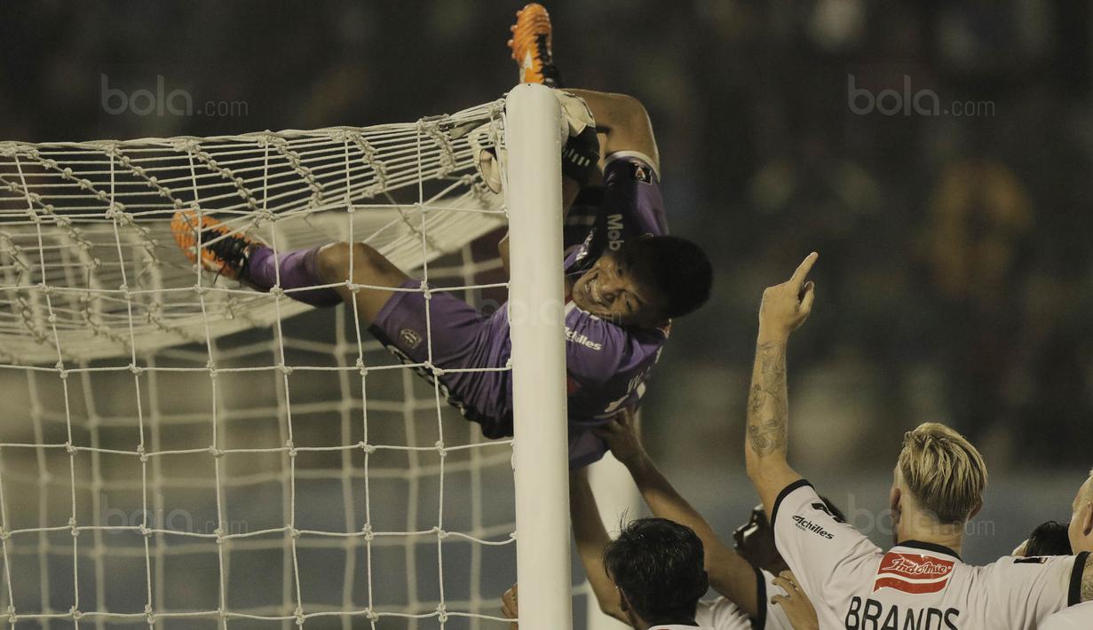 Kiper Bali United, Wawan Hendrawan, melakukan selebrasi panjat tiang gawang usai mengalahkan Madura United pada laga Piala Presiden di Stadion Manahan, Solo, Sabtu, (3/2/2018). Bali United menang adu penalti dengan skor 5-4. (Bola.com/M Iqbal Ichsan)