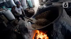 Pekerja mengolah kacang dengan media pasir di salah satu industri rumahan pembuatan kacang sangrai di Kawasan Keranggan, Tangerang Selatan, Selasa (11/8/2020). Kacang sangrai yang dipasarkan seharga Rp10.000 per kg itu mulai mengalami kenaikan pesanan dibanding bulan lalu. (merdeka.com/Dwi Narwoko)