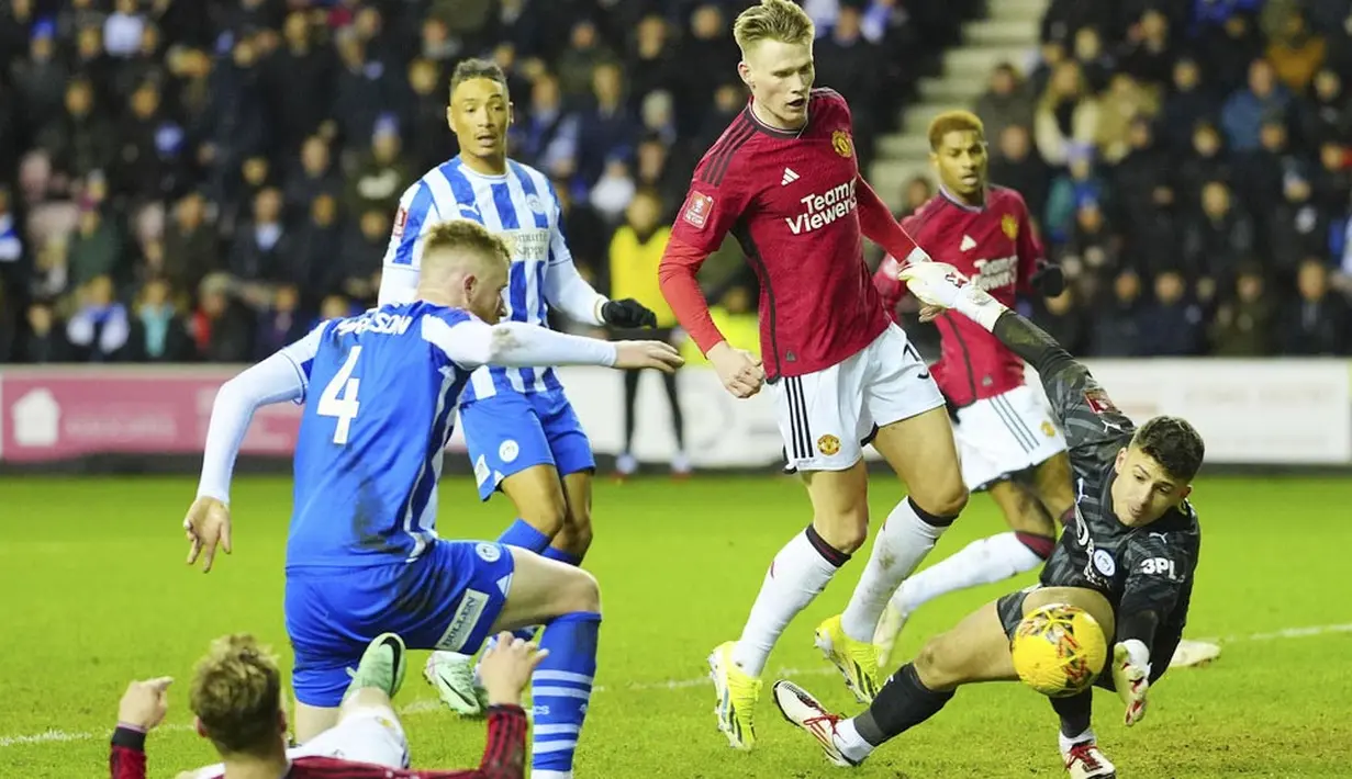 Kiper Wigan Athletic, Sam Tickle, berusaha menghalau bola saat melawan Manchester United dalam laga putaran ketiga FA Cup 2023/2024 di DW Stadium, Selasa (9/1/2024) dini hari WIB. Dua gol kemenangan Manchester United masing-masing diciptakan oleh Diogo Dalot dan Bruno Fernandes. (AP Photo/Jon Super)