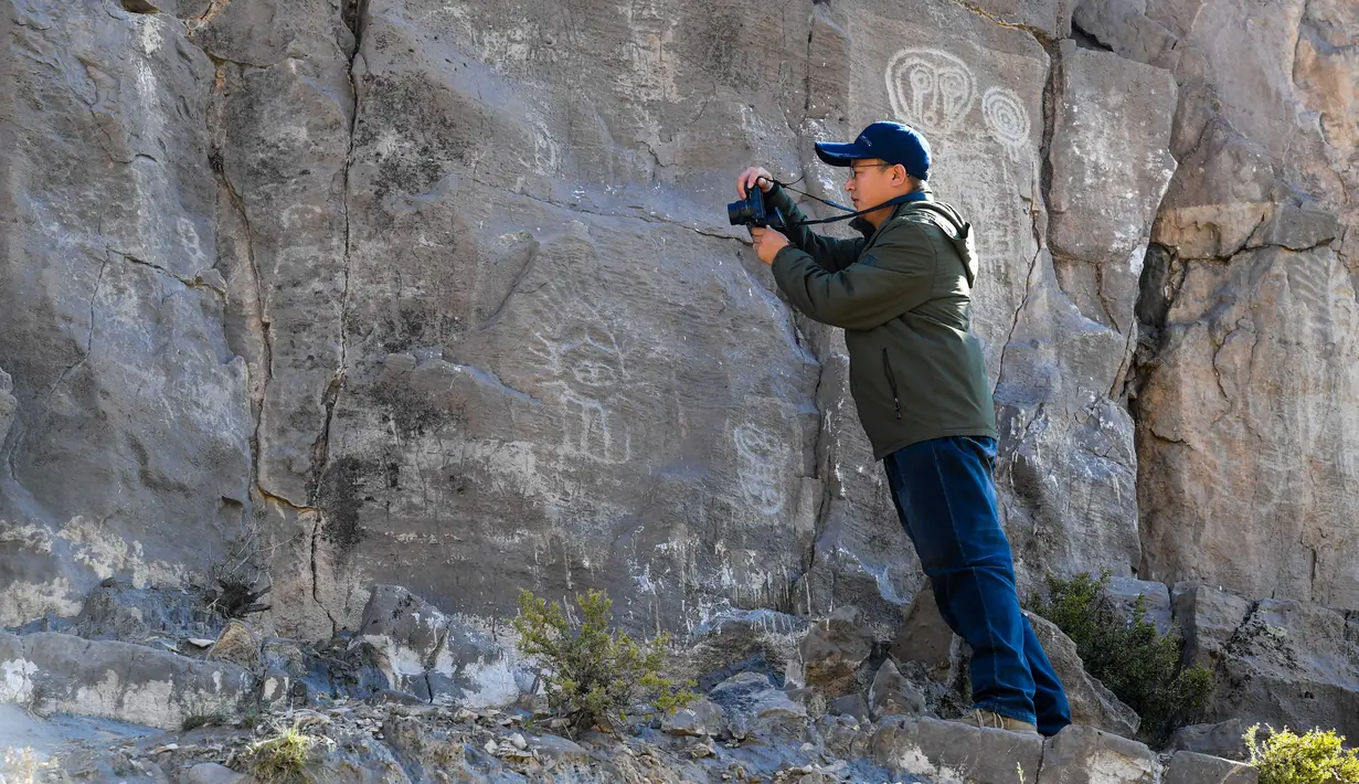 Seorang arkeolog memotret lukisan batu di klaster seni cadas Gunung Zhuozi di Daerah Otonom Mongolia Dalam, China pada 17 Oktober 2020. Gunung Zhuozi adalah tempat dengan banyak lukisan batu yang berguna untuk penelitian tentang asal muasal nomad kuno di China. (Xinhua/Peng Yuan)