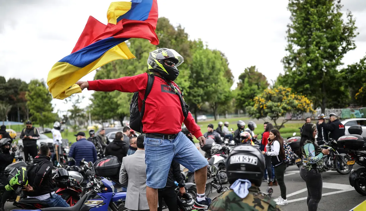 Seorang pengendara sepeda motor mengibarkan bendera selama protes kenaikan harga bahan bakar dan asuransi wajib pihak ketiga di Bogota, Kolombia, Rabu (12/10/2022). Aktivis berkumpul di luar Perpustakaan Virgilio Barco, yang terletak di dekat Simon Bolivar Central Park, mulai pukul 07:30. (AP Photo/Ivan Valencia)