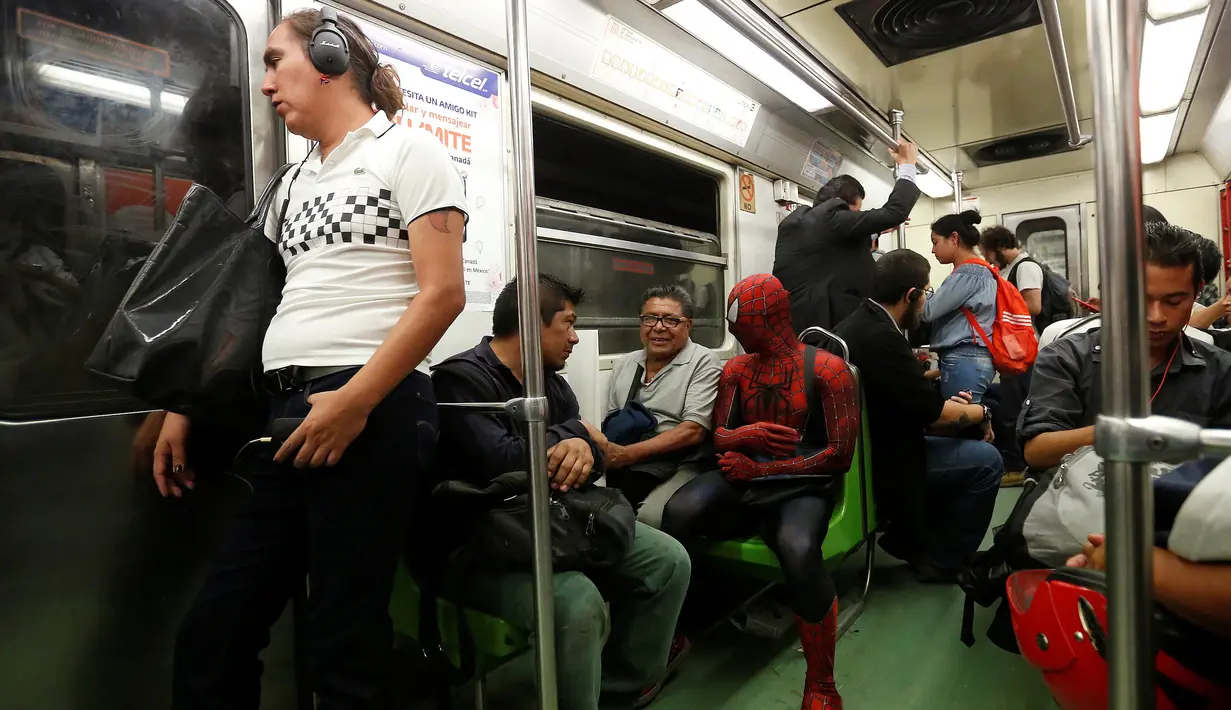Moises Vazquez berbincang dengan penumpang kereta menuju Universitas Otonomi Nasional Meksiko (UNAM) di Meksiko City, Meksiko, 27 Mei 2016. Pria 26 tahun ini sering kali menggunakan kostum spiderman ketika pergi mengajar. (REUTERS/Edgard Garrido)