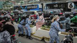Sejumlah perserta yang tergabung dalam Forum Kader Bela Negara DKI Jakarta membagikan bunga dan masker kepada pengguna jalan di Jalan Thamrin, Jakarta, Rabu (22/12/2021). Aksi tersebut merupakan bentuk apresiasi terhadap kaum perempuan terutama pada peringatan Hari Ibu. (Liputan6.com/Faizal Fanani)