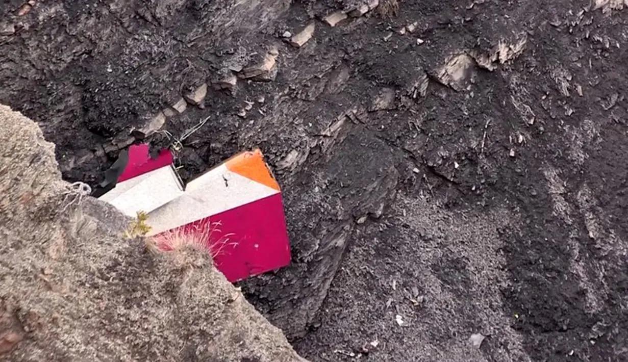 Bagian pesawat Germanwings berwarna merah, putih, kuning terlihat menyelip di bebatuan pegunungan Alpen, Prancis, Selasa (24/3/2015). Pesawat itu jatuh dalam perjalanan dari Barcelona menuju Dusseldorf, Jerman. (AFP PHOTO /DENIS BOIS /GRIPMEDIA /AFP TV)