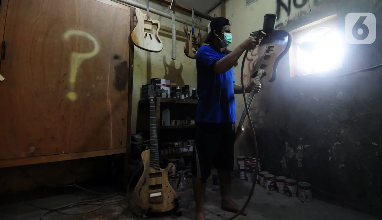 Pekerja menyelesaikan pembuatan gitar listrik Syukey Instrumen di kawasan Ciputat Timur, Tangerang Selatan, Banten, Selasa (26/10/2021). Dalam sebulan, pekerja mampu memproduksi 3 - 4 gitar listrik dengan harga Rp 3,5 juta hingga Rp 45 juta. (merdeka.com/Arie Basuki)