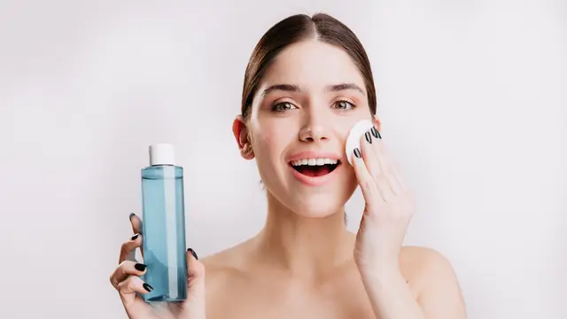 Seorang perempuan sedang membersihkan wajahnya menggunakan micellar water (Foto Dok: Freepik/lookstudio)