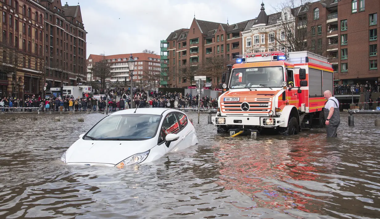 Sebuah mobil diselamatkan dari air banjir oleh pemadam kebakaran setelah badai di Hamburg, Jerman, Minggu (30/1/2022).Badai musim dingin yang kuat melanda Eropa utara selama akhir pekan. (Daniel Bockwoldt/dpa via AP)