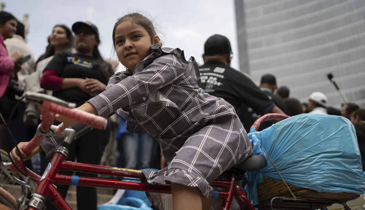 Seorang gadis duduk di atas sepeda penjual taco saat acara pemecahan rekor taco terbanyak yang disajikan dalam satu jam — 30.000 — di monumen Angel of Independence di Mexico City, Minggu, 11 Agustus 2024. (AP Photo/Aurea del Rosario)